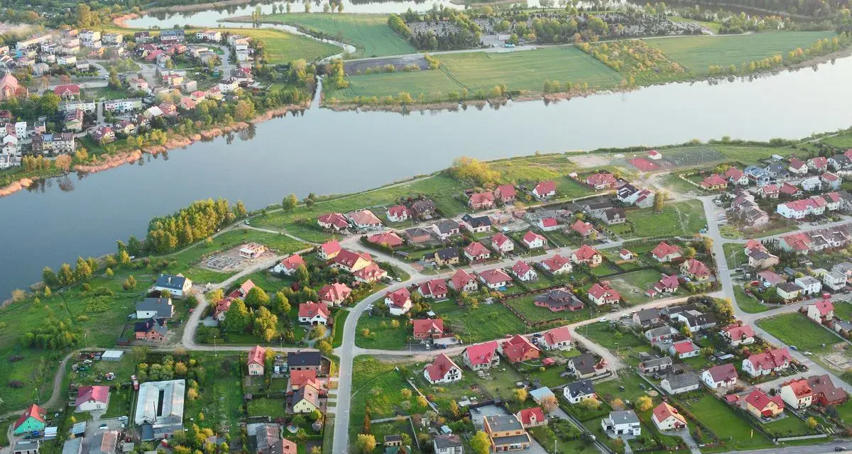 Widok z lotu ptaka na malownicze jezioro Pniewy otoczone zielenią i zabudowaniami.