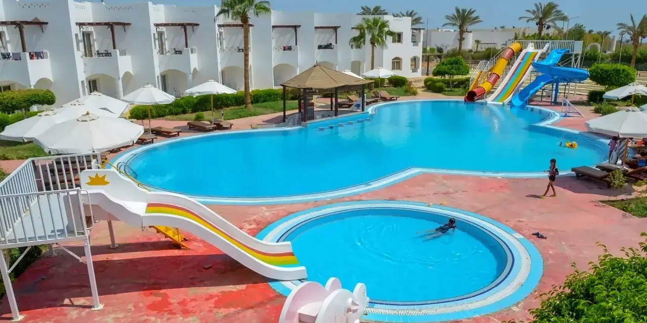 Egipt last minute all inclusive najtaniej: basen z wodnymi zjeżdżalniami i palmami, idealny na wakacje.