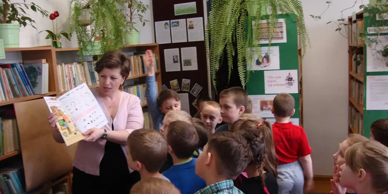 Nauczycielka czyta dzieciom książkę, tworząc inspirujące lekcje biblioteczne scenariusze. Dzieci słuchają z uwagą.