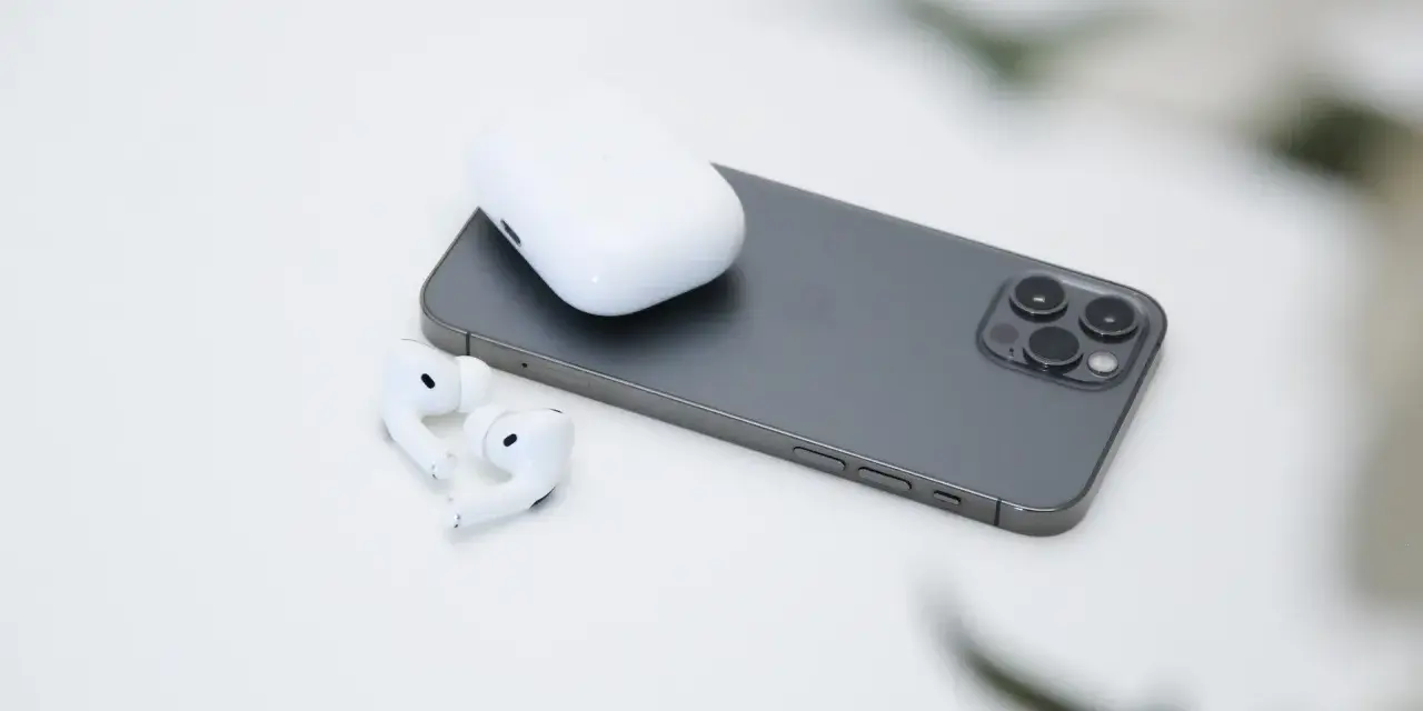 AirPods und Ladecase liegen neben einem Smartphone.