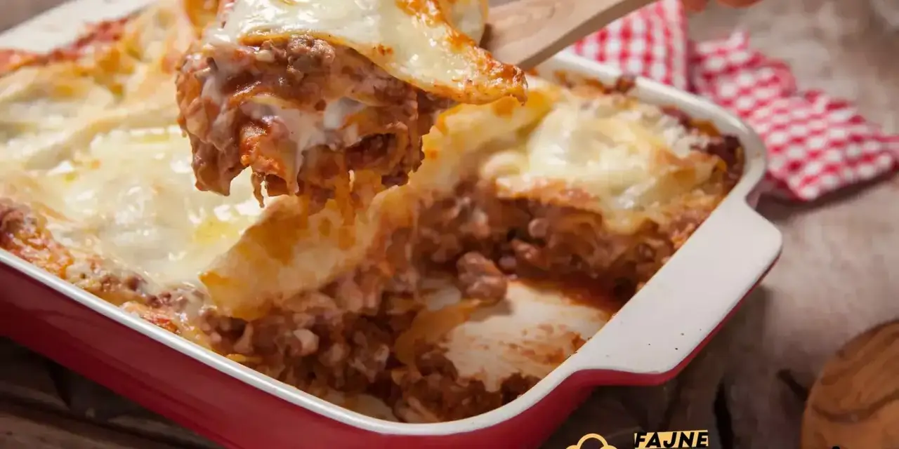 Pyszna, gorąca lasagne z mięsem mielonym i ciągnącym serem, właśnie nakładana drewnianą łopatką. Idealna na rodzinny obiad.