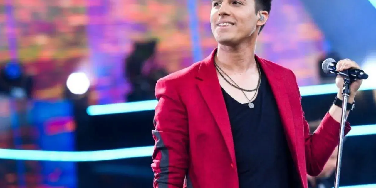 Filip śpiewa na scenie w czerwonej marynarce. Lato i jego żona pewnie są na widowni.