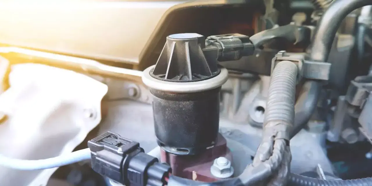 Dettaglio di un componente del motore, la valvola EGR, con connettori elettrici e tubi nelle vicinanze.