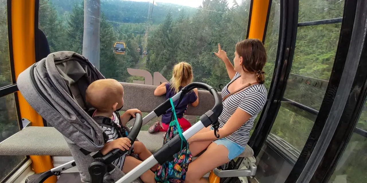 Rodzina w kolejce gondolowej w Górach Izerskich, Świeradów-Zdrój. Dzieci zachwycone widokiem lasu i innych wagoników.