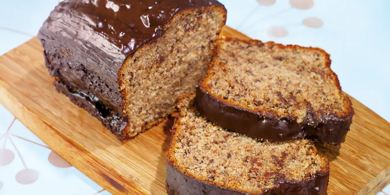 Saftiger Kuchen mit Bananen und Schokoladenglasur, auf einem Holzbrett serviert.