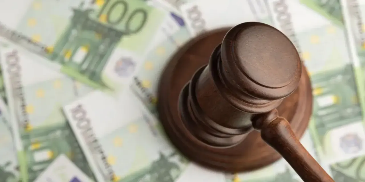 Młotek sędziowski na tle banknotów 100 euro.