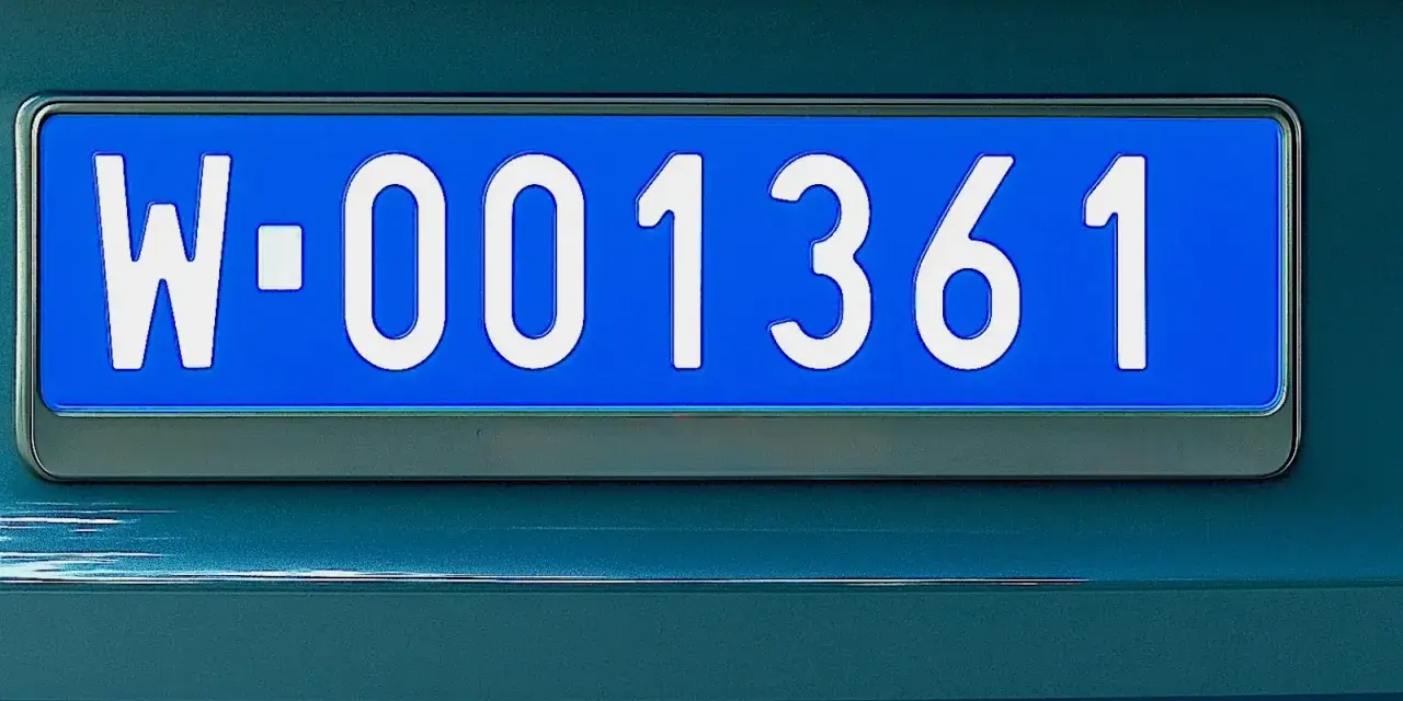 Niebieska tablica rejestracyjna z białymi znakami: W-001361.