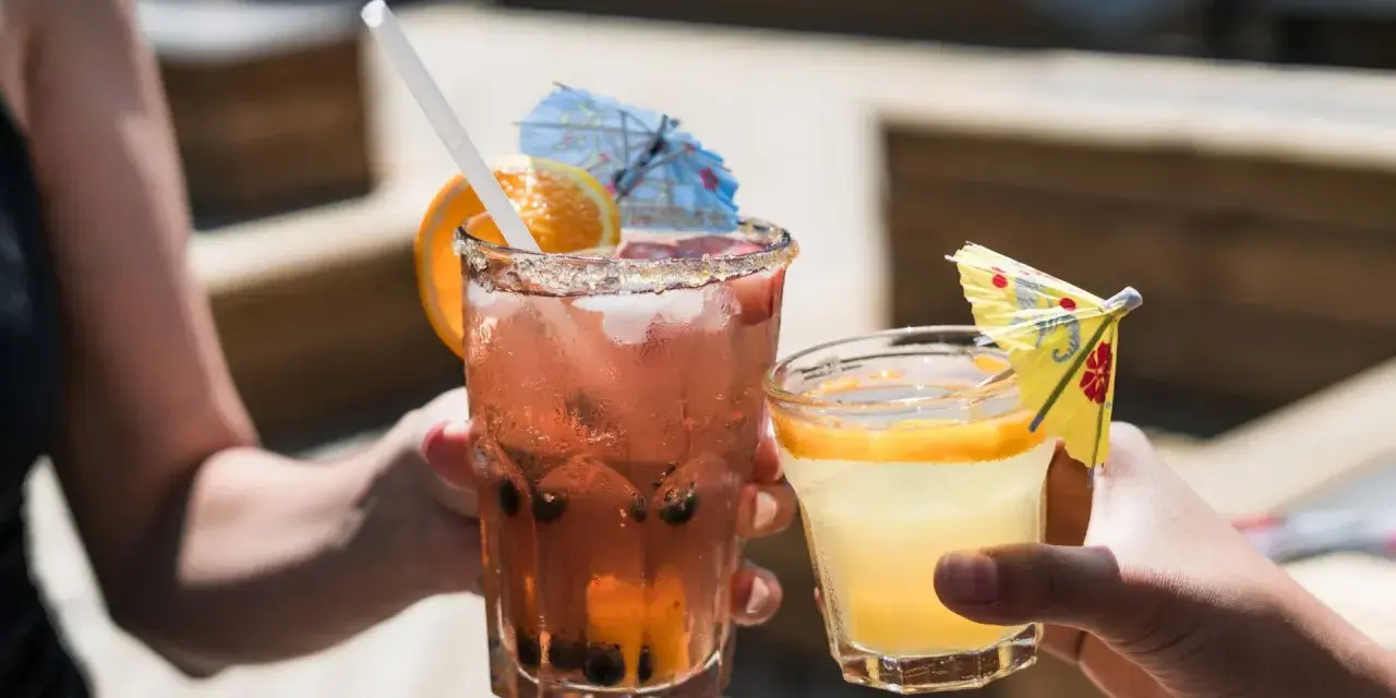 Dwa orzeźwiające drinki, jeden różowy z owocami i pomarańczą, drugi żółty z plasterkiem pomarańczy. Idealne na letnie popołudnie, może z dodatkiem białego wina.