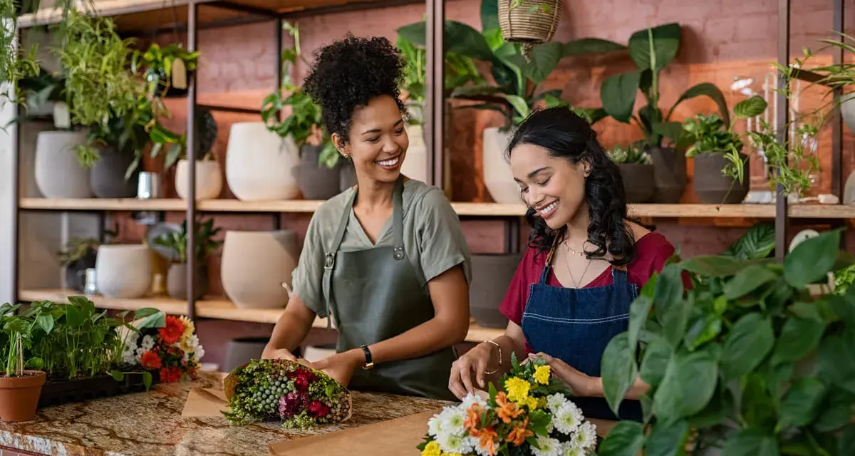 Deux fleuristes souriantes créent des bouquets. Un métier artistique bien payé qui embellit le quotidien.