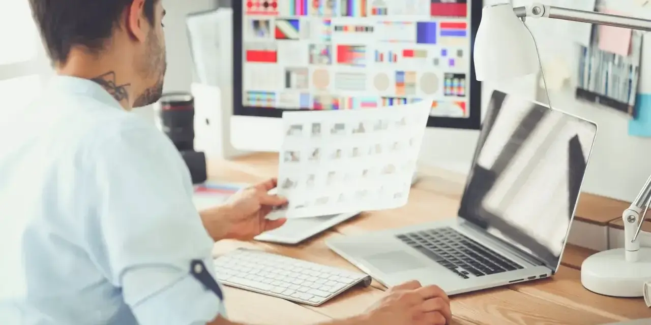 UX designer analizuje wydruki i ekran komputera z paletą barw.