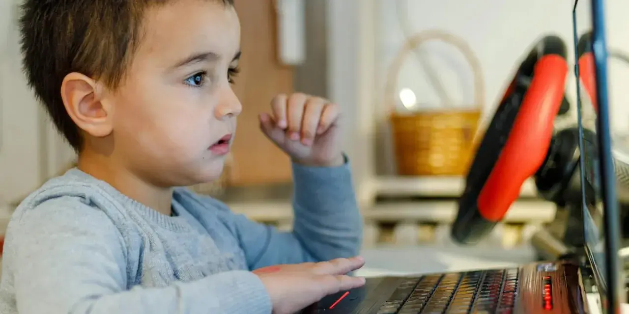 Chłopiec z zaciekawieniem ogląda na laptopie materiały o biologii dla dzieci.
