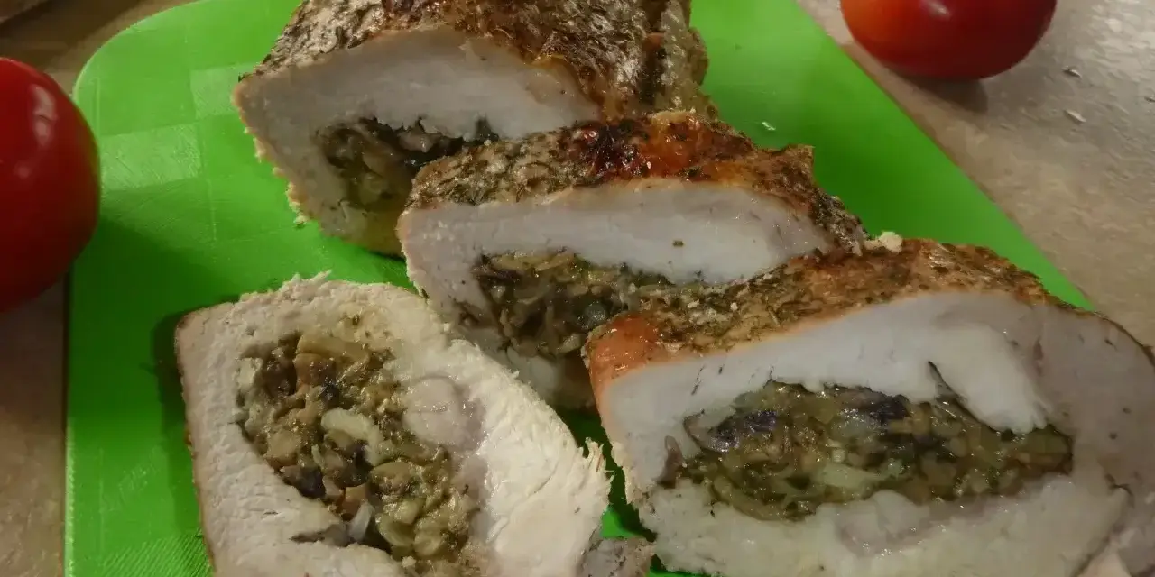 Pyszny kotlet husarski, pieczony z ziołami i nadzieniem grzybowym, pokrojony na desce.