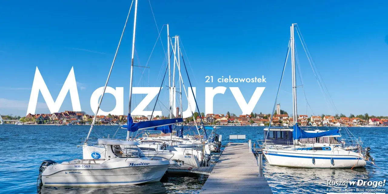 Żaglówki cumujące w porcie na Mazurach, Polska. W tle malownicze miasteczko nad jeziorem.