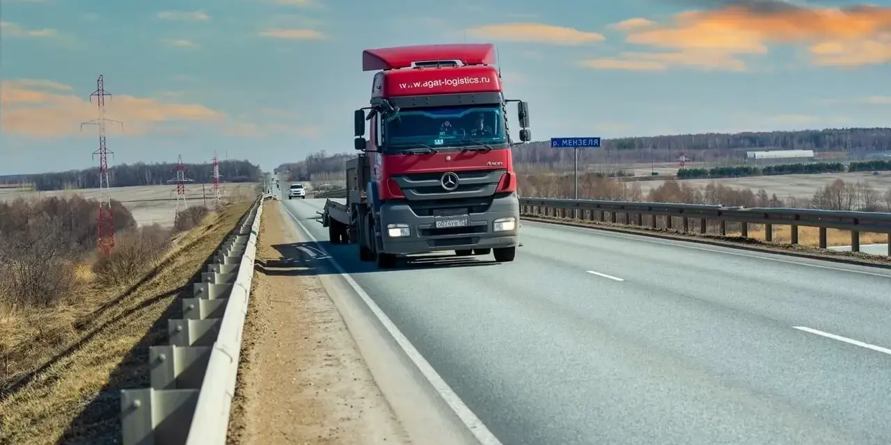Czerwona ciężarówka jedzie autostradą. Ubezpieczenie kabotażowe zapewnia spokój podczas międzynarodowych transportów.