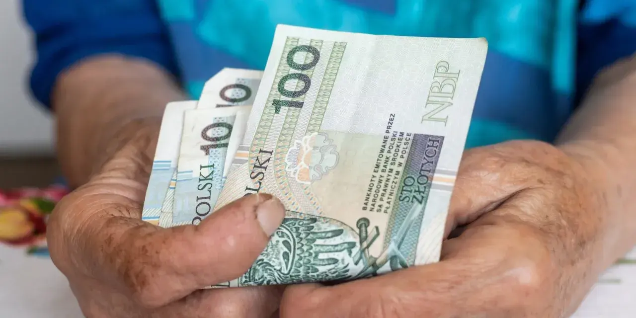 Dłonie starszej osoby trzymają banknoty 100 zł. To może być ta długo wyczekiwana 14 emerytura.
