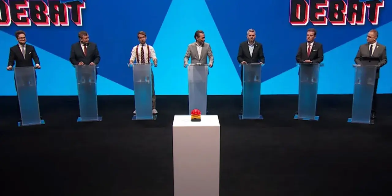 Siedmiu mężczyzn w garniturach stoi za mównicami. W tle logo "Liga Debat #2".