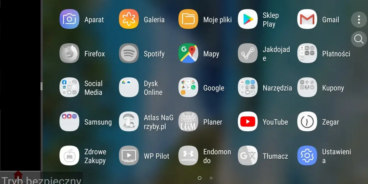 Ekran telefonu z ikonami aplikacji. Widoczny jest pasek "Tryb bezpieczny", co sugeruje, jak włączyć tryb awaryjny w telefonie.