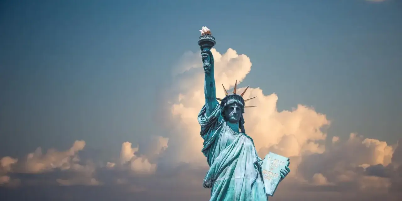 Statua Wolności z pochodnią w górze, symbol USA. Planujesz podróż? Pamiętaj o ubezpieczeniu turystycznym USA.