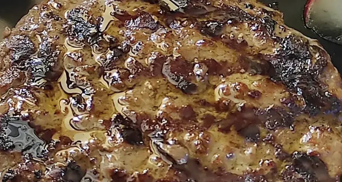 Hamburger in padella succulento, con crosticina dorata e succo che cola. Perfetto per un pasto veloce e gustoso.