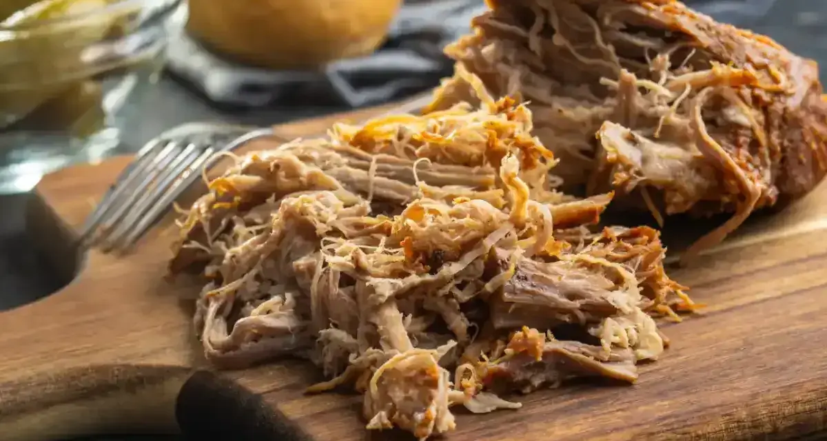 Un délicieux effiloché de porc, tendre et savoureux, prêt à être dégusté sur une planche en bois.