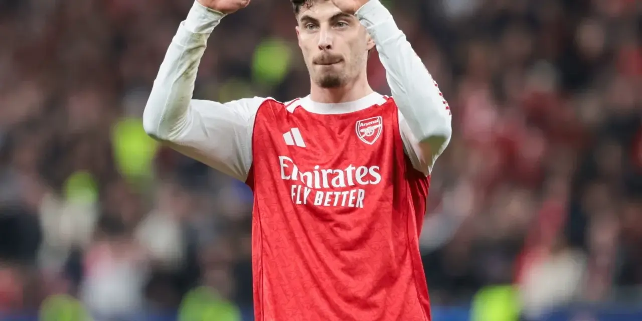 Piłkarz Arsenalu świętuje klasyczny hattrick, wznosząc pięści w geście triumfu na tle trybun.