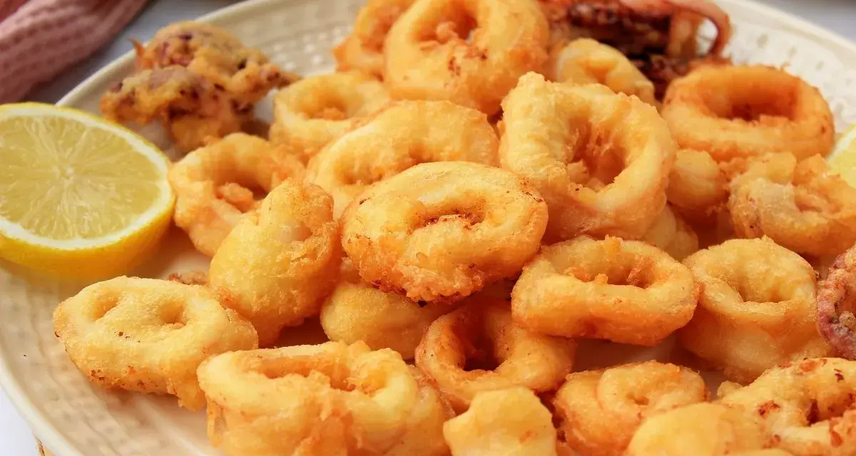 Plato de calamares a la romana dorados y crujientes, servidos con rodajas de limón fresco.