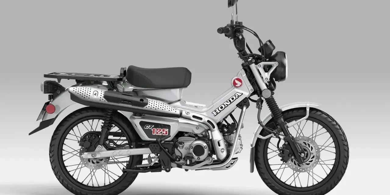 Srebrny motocykl Honda CT 125 z czarnym siedzeniem i bagażnikiem, gotowy na przygodę.