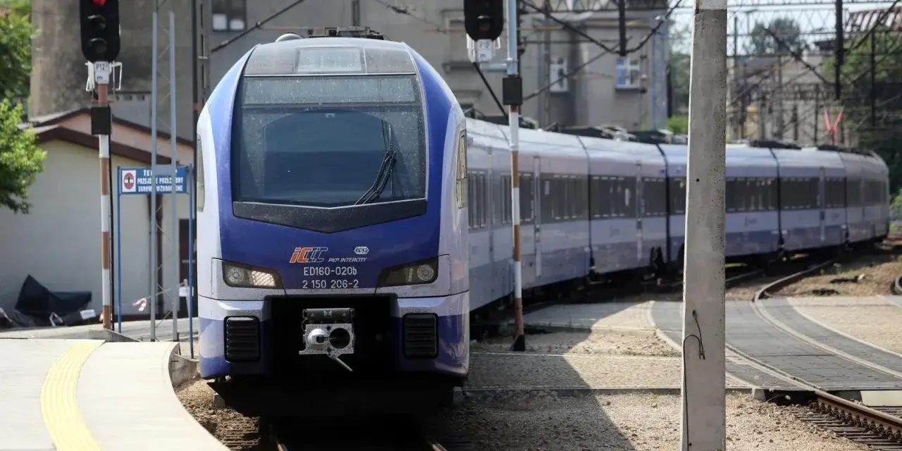 Niebiesko-biały pociąg PKP Intercity ED160-020b stoi na stacji.