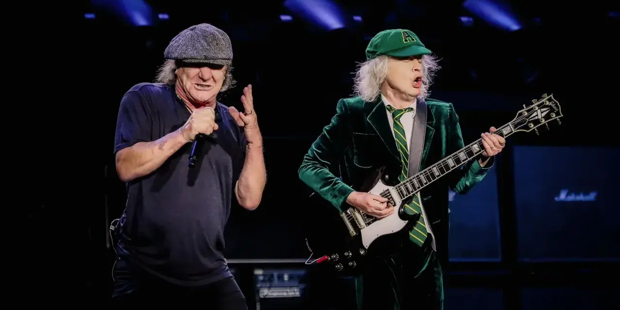 Brian Johnson i Angus Young, legendarny skład AC/DC, na scenie. Brian śpiewa do mikrofonu, Angus gra na gitarze.