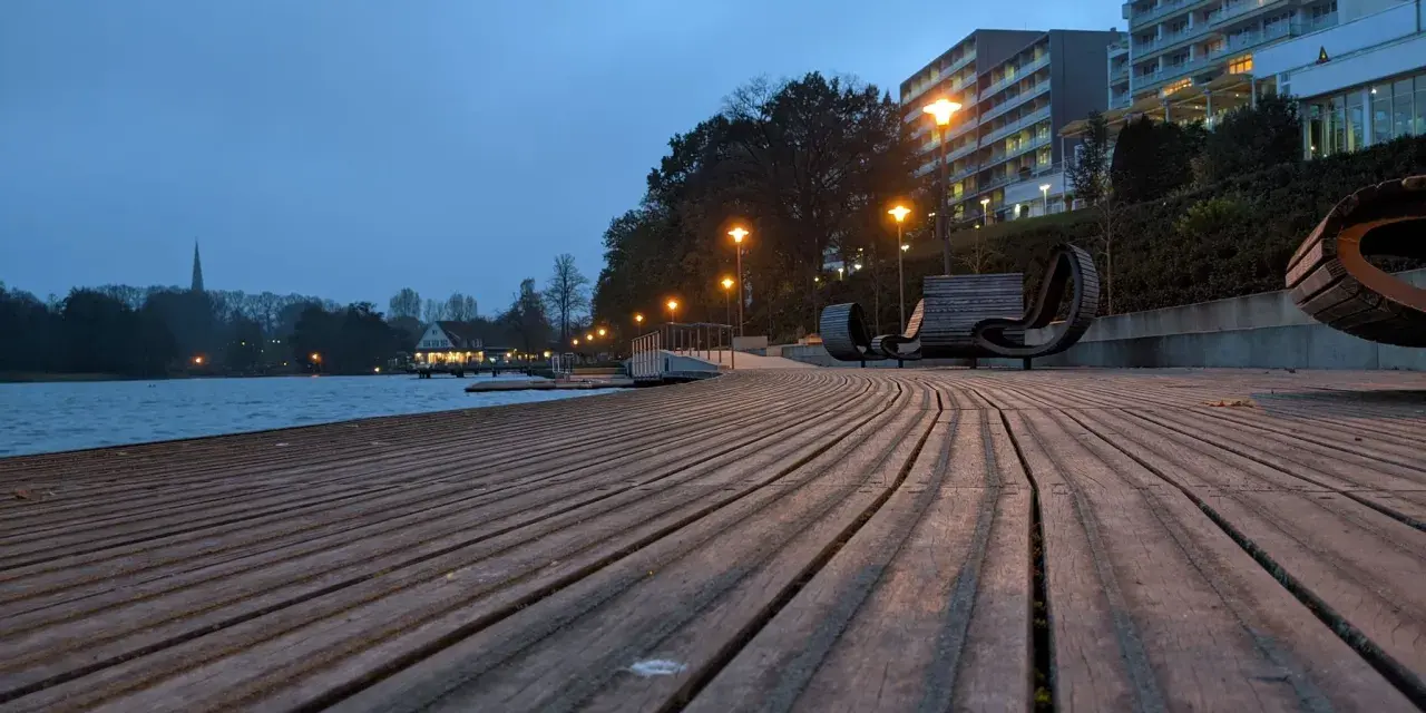 Holzdeck am See mit modernen Bänken und Beleuchtung. Ein schöner Ort für **Bad Segeberg Unternehmungen** am Abend.