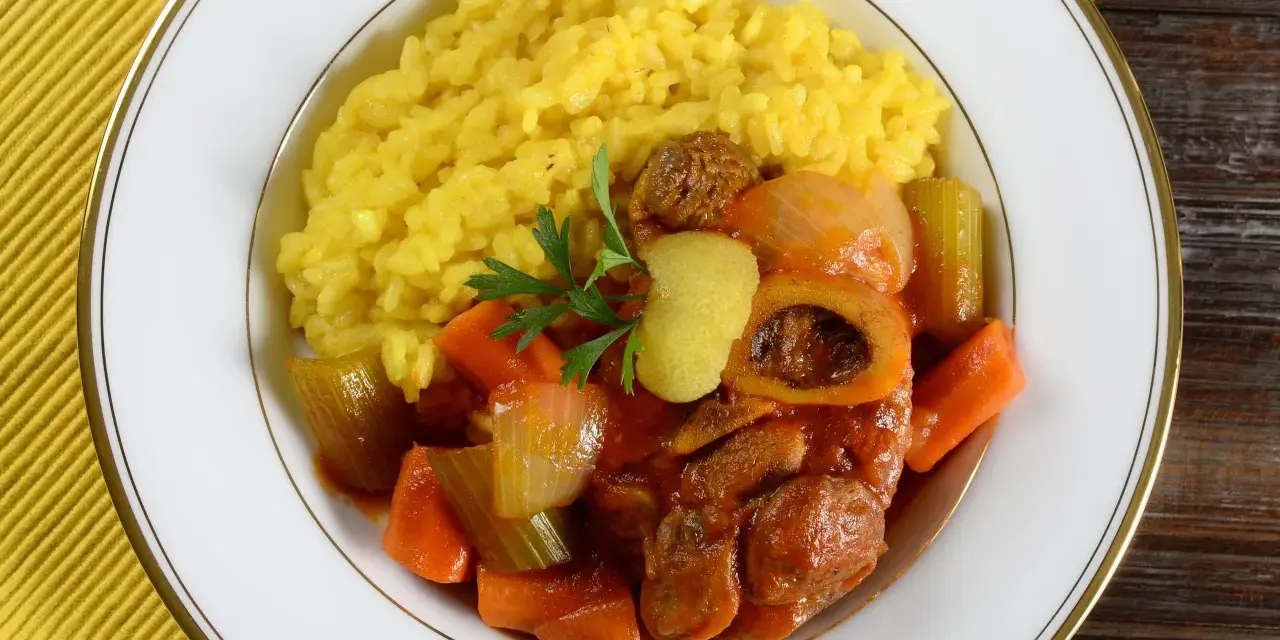 Risotto giallo e ossobuco con verdure, un classico dei piatti tipici milanesi, guarnito con prezzemolo e scorza di limone.