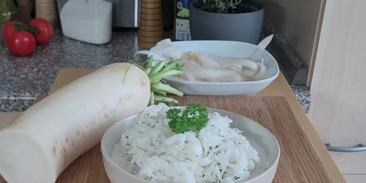 Ein frischer Rettichsalat, zubereitet nach einem einfachen Rettichsalat Rezept, garniert mit Petersilie. Daneben liegt ein ganzer Rettich.
