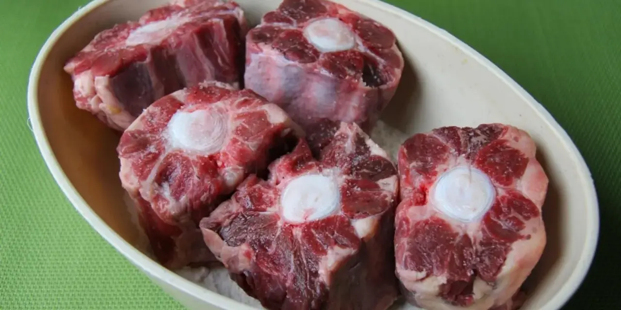 Trozo de rabo de ternera crudo en un cuenco, con el hueso central visible.