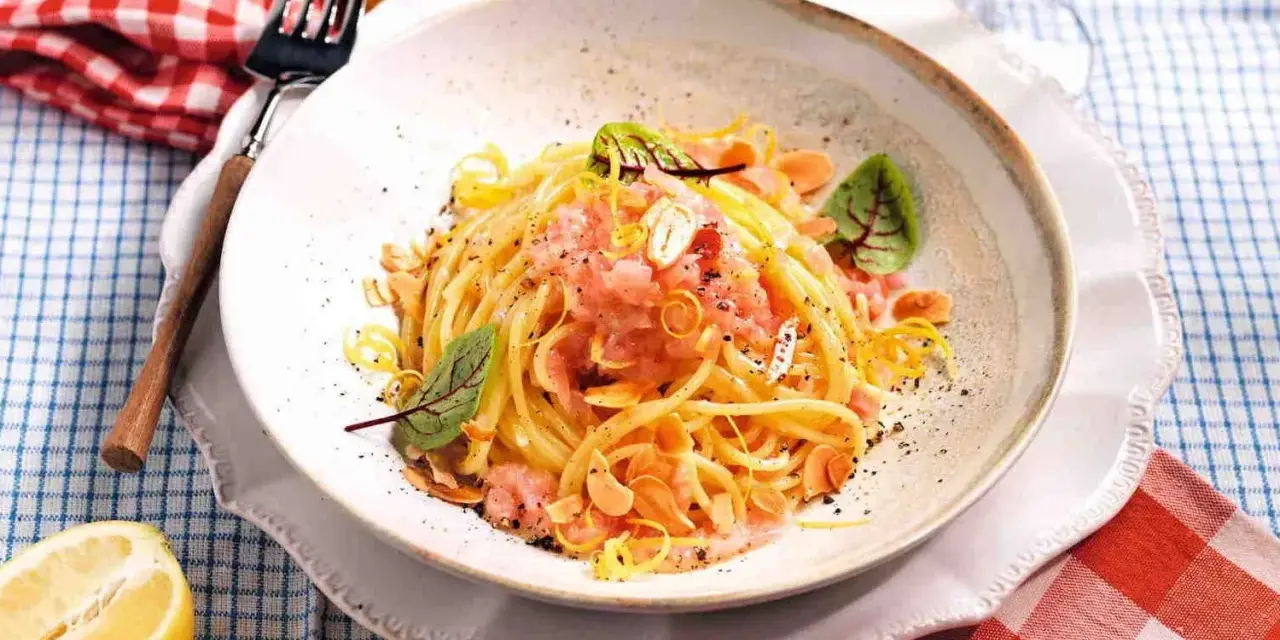 Spaghetti con sughi in bianco, conditi con limone, mandorle e un tocco di rosa.