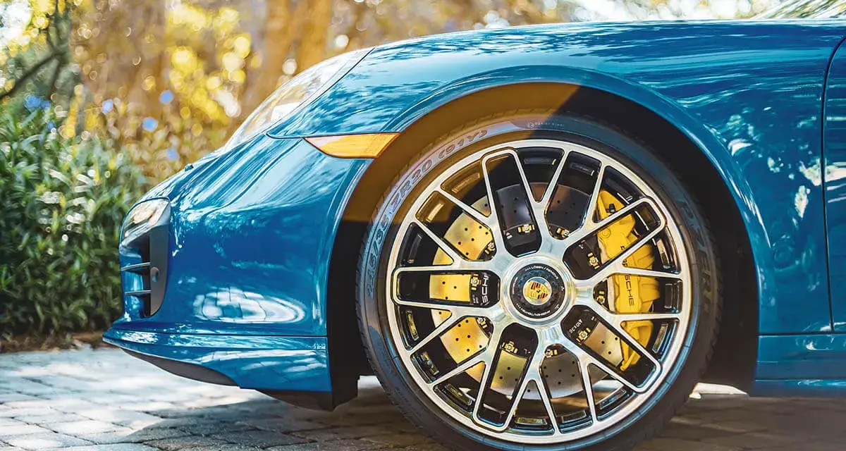 Błękitne Porsche z żółtymi zaciskami hamulcowymi i wieloramiennymi felgami. To jest et felgi, które dodają sportowego charakteru.