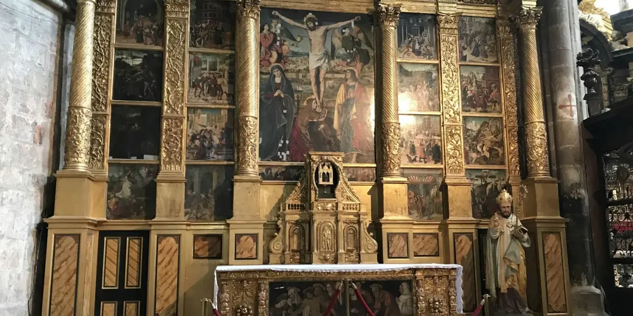 The ornate altar of the Basilica of Mary Magdalene features a central crucifixion scene surrounded by smaller narrative paintings, all set within a gilded structure.