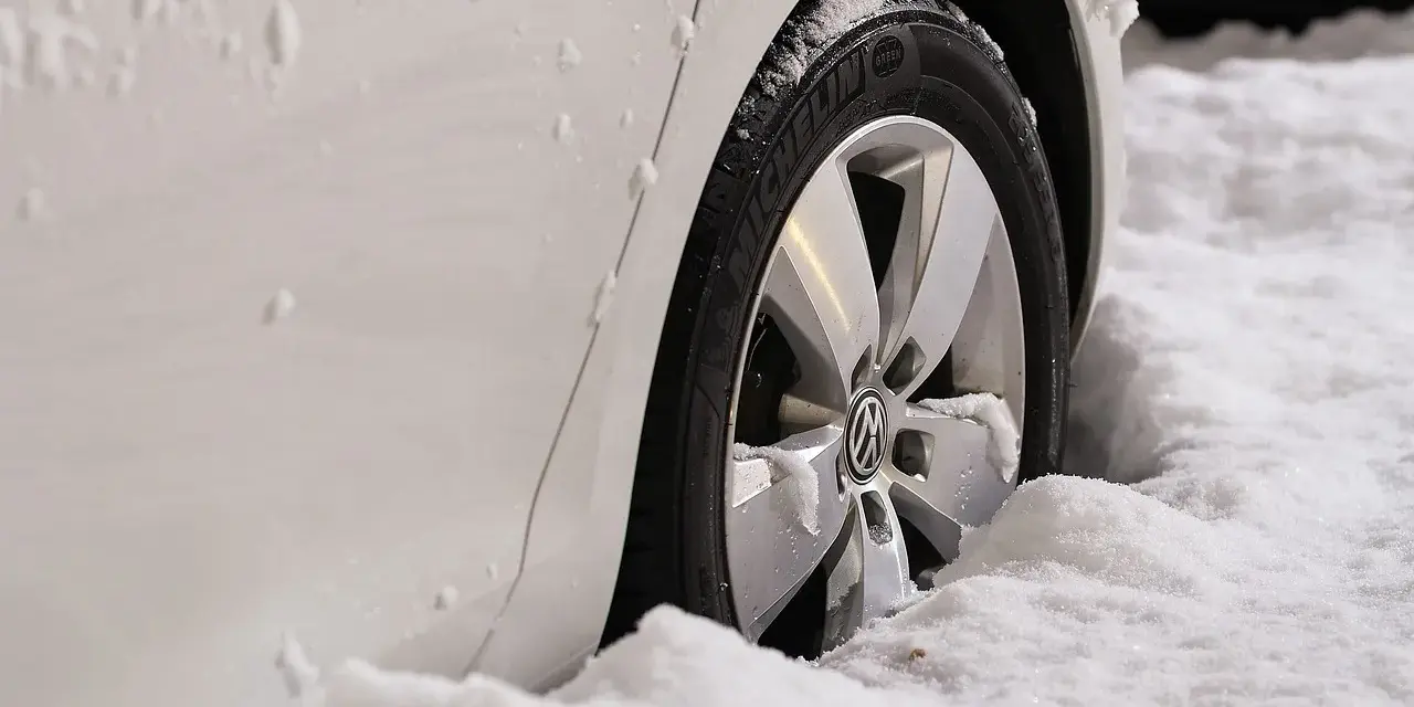 Białe auto w śniegu, widoczna felga z logo VW. Zastanawiasz się, jak zmierzyć rozstaw śrub?