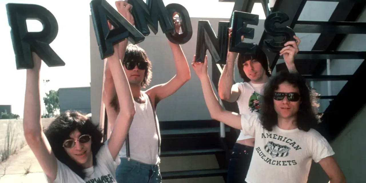 Vier Männer halten die Buchstaben des **titels von Ramones** hoch. Sie tragen Sonnenbrillen und Band-T-Shirts.