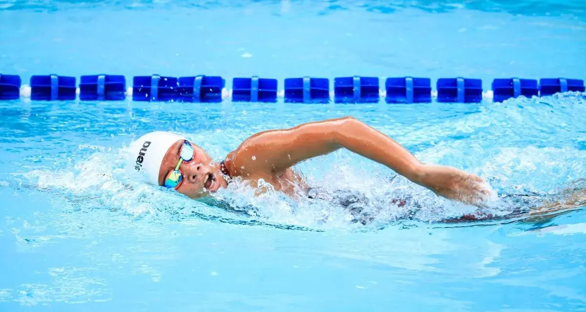 Un nageur concentré en pleine séance natation, la tête hors de l'eau, les bras en mouvement dans la piscine.