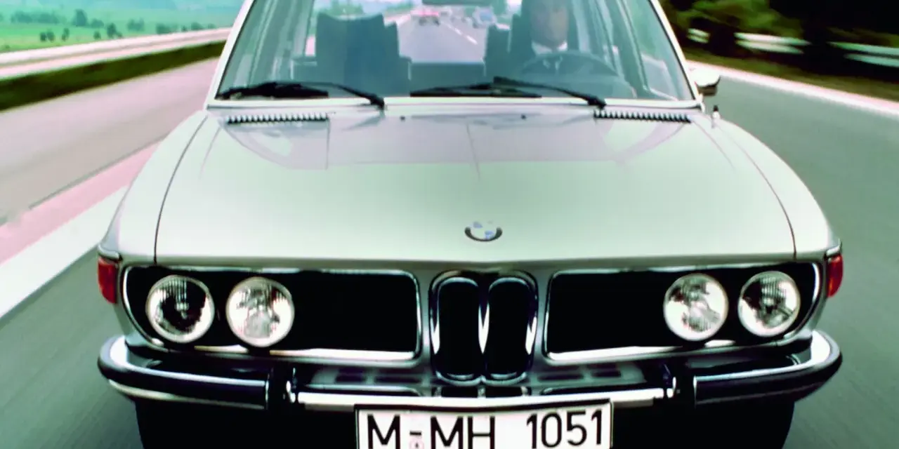 Srebrne BMW E3 z lat 70. jedzie po drodze.