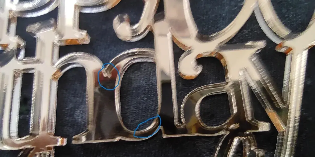 Close-up of a "Happy Birthday" acrylic mirror cake topper, showing the delicate edges and some minor imperfections from how to cut acrylic mirror.