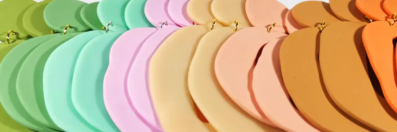 Fimolera smycken i pastellfärger, arrangerade i en mjuk kurva. Grönt, mintgrönt, rosa, beige och orange skapar en drömsk färgpalett.