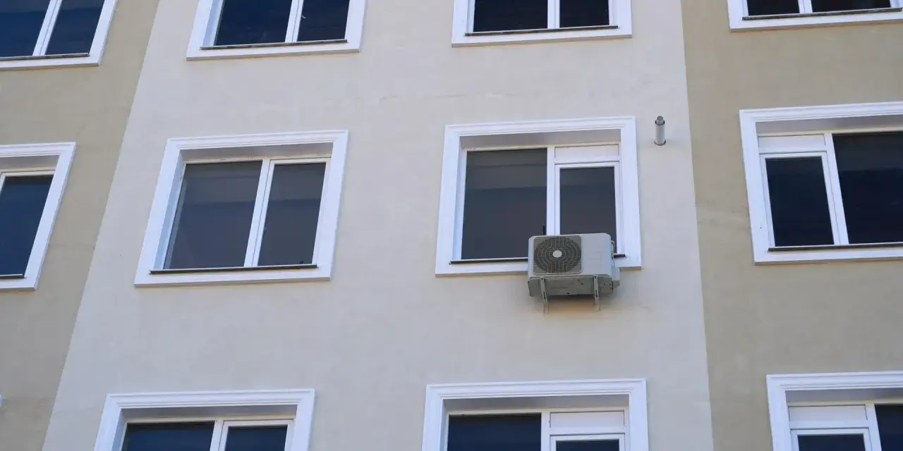 Klimatyzacja w bloku, zamontowana na ścianie między oknami, zapewnia komfort mieszkańcom.