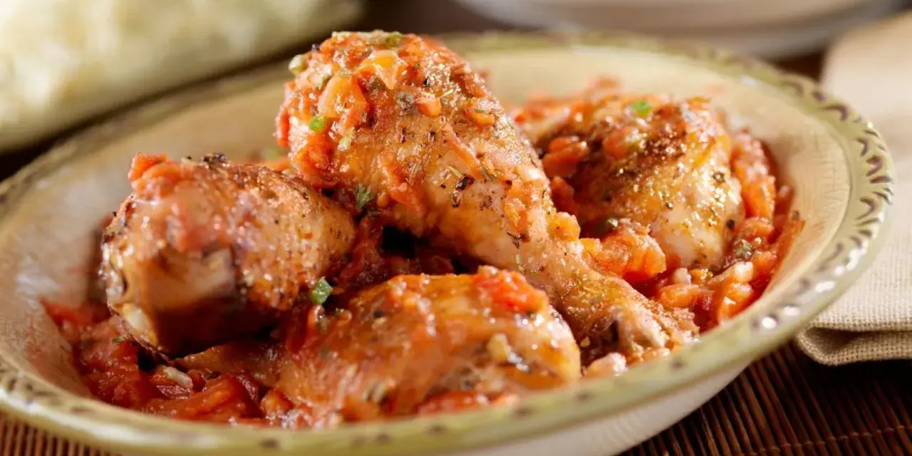 Pollo en salsa de tomate con hierbas, servido en un cuenco rústico.