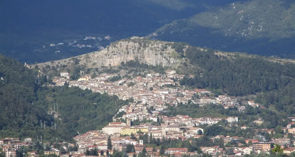 Borgo abruzzese arroccato su un colle, tra boschi e montagne. Immagina il **cammino dei briganti Abruzzo** che attraversa questi sentieri selvaggi.