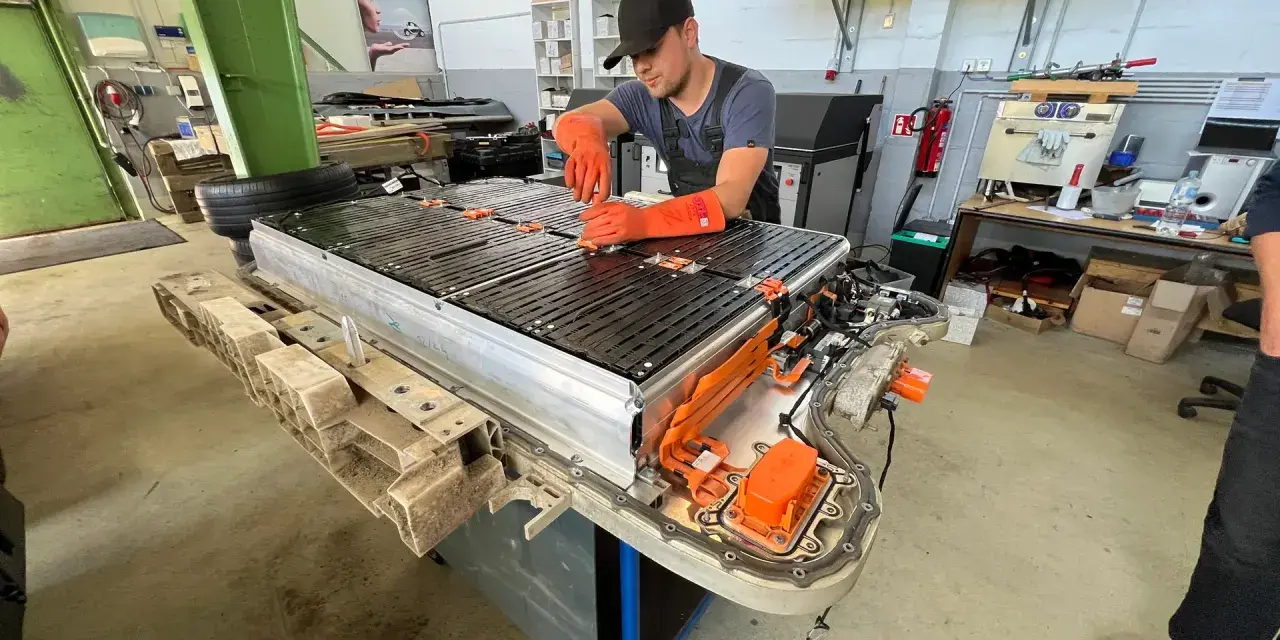 Mechaniker arbeitet an einer großen Batterieeinheit, die für Elektroautos bestimmt ist. Dies ist wichtig für die **Autobatterie Garantie**.