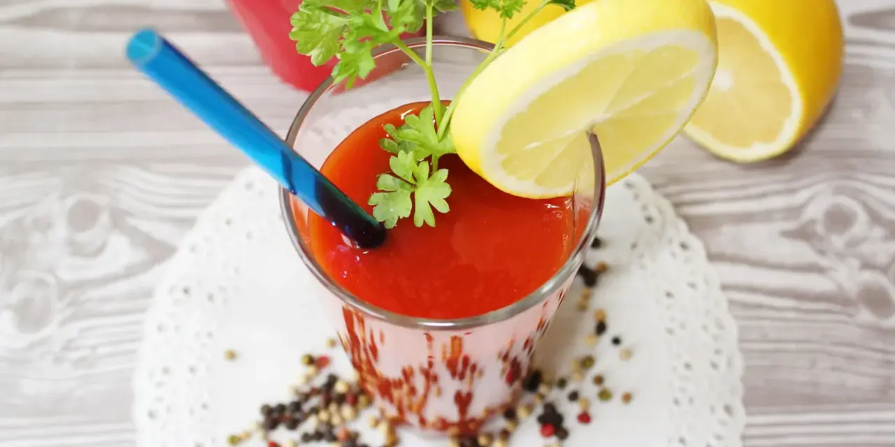 Orzeźwiający drink z sokiem pomidorowym, ozdobiony plasterkiem cytryny i natką pietruszki, gotowy do wypicia.