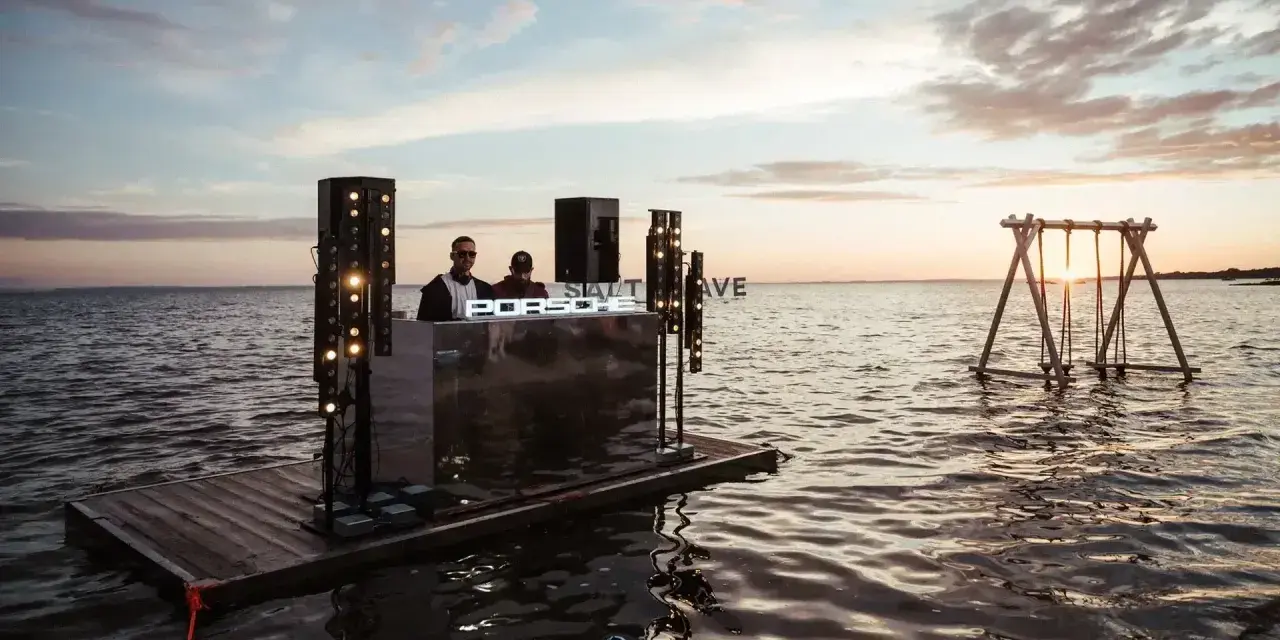 DJ na wodnej platformie podczas Salt Wave Festival. W tle huśtawka na jeziorze o zachodzie słońca.