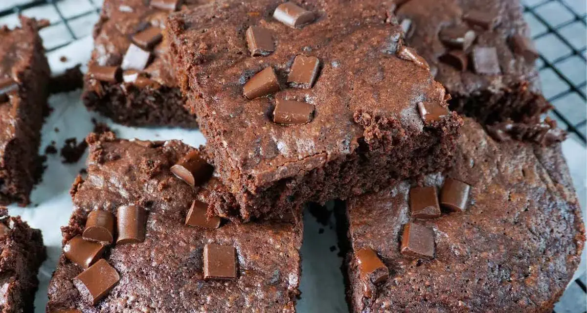 Saftige Zucchini Brownies mit Schokostückchen, die auf einem Gitterrost liegen.
