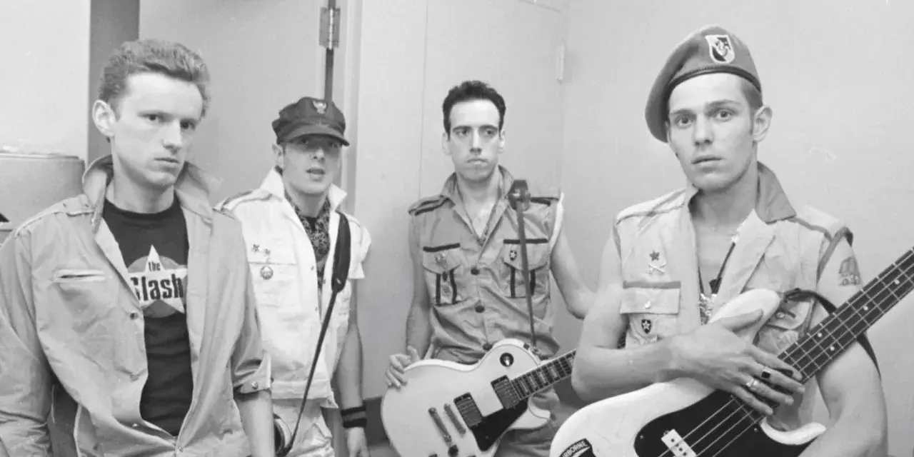 Les membres de The Clash posent avec leurs guitares. L'un porte un t-shirt "The Clash".